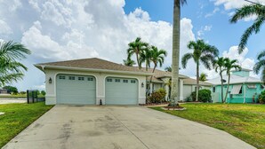 A residential house with two garage doors, a driveway, and palm trees. - Spectacular Views! Largest Canal in NW Cape Coral (Cape Coral)