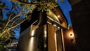 A modern building with a well-lit entrance, a potted plant, and a visible door. - Aluna Ubud Villas (Ubud)