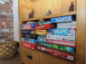 A wooden cabinet with various board games stacked on shelves. - Llanallgo Church Rooms (Moelfre)