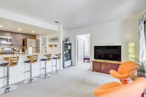 A modern kitchen with stainless steel appliances, a dining area with bar stools, a living room with a flat-screen TV, and a bright, airy space. - 2 Mi to Dtwn! Chic Palm Springs Condo (Palm Springs)