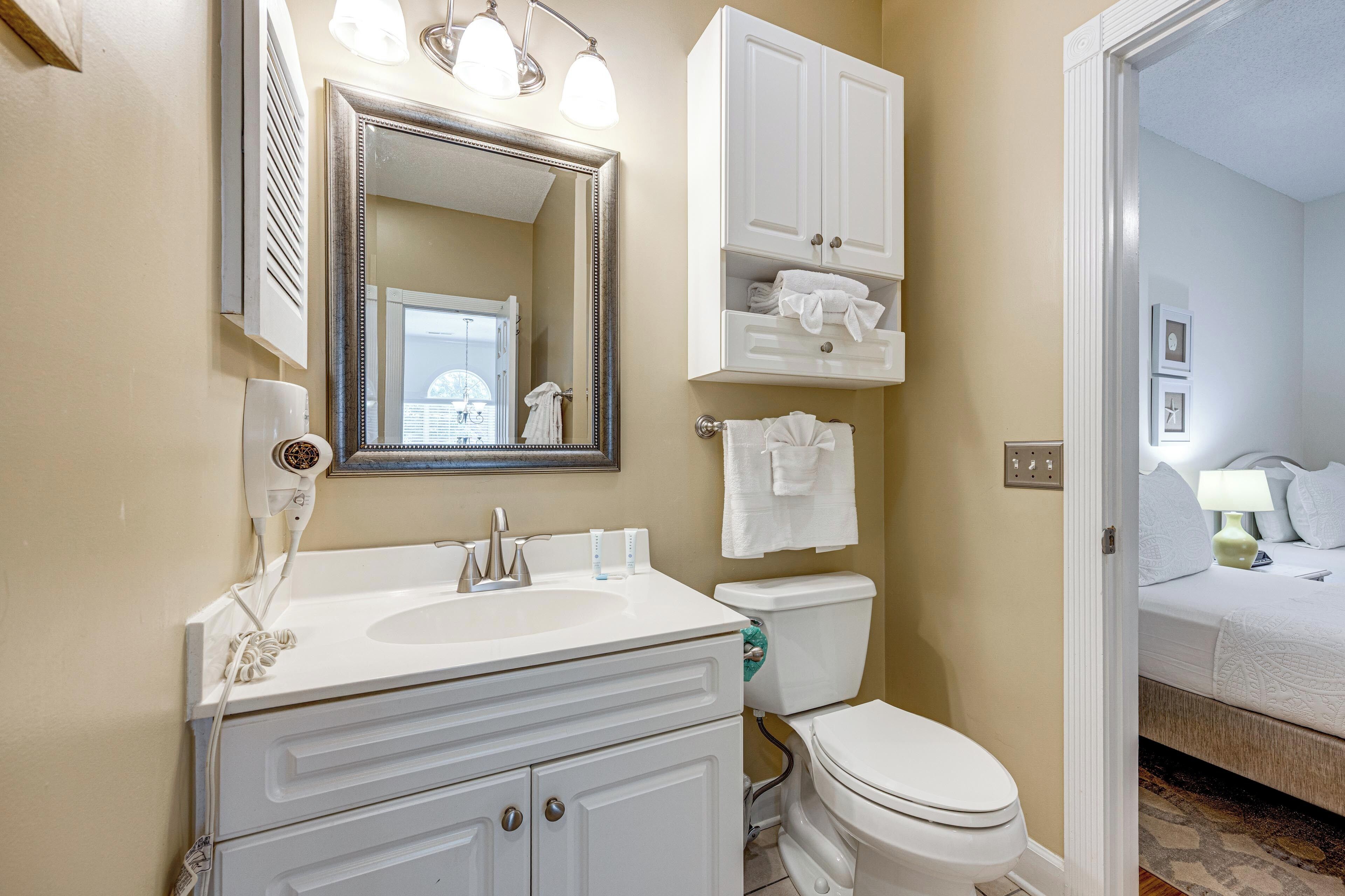 A bathroom with a sink, mirror, toilet, and a cabinet above the toilet.