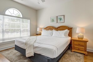 A bedroom with a large bed, two bedside tables, a window with blinds, and two wall-mounted pictures. - Myrtle Beach Golf Getaway! Snowbirds Welcome (Myrtle Beach)