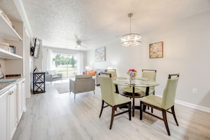 A dining area with a round glass table, four chairs, a ceiling fan, and a view of the outdoors. - Tee Times & Poolside Vibes! Myrtle Beach Retreat (Myrtle Beach)