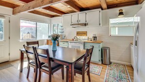 Una cucina con travi in legno, mobili bianchi, un tavolo da pranzo con sedie e una finestra con vista.