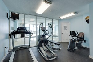 Un gimnasio con cintas de correr, elípticas y una bicicleta estática.
