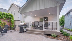 A covered patio with outdoor furniture, a grill, and a brick wall with climbing plants. - Tremont Retreat w/ Putting Green Near Downtown (Cleveland)