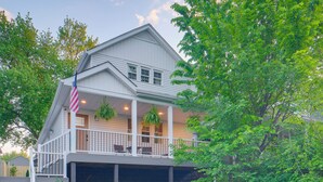 A two-story house with a covered porch, a flag, and hanging plants. - Tremont Retreat w/ Putting Green Near Downtown (Cleveland)