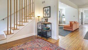 A staircase with wooden steps and a black metal console table with storage. - Yard & Fire Pit! Chic Retreat, 2 Mi to Ford Field (Detroit)