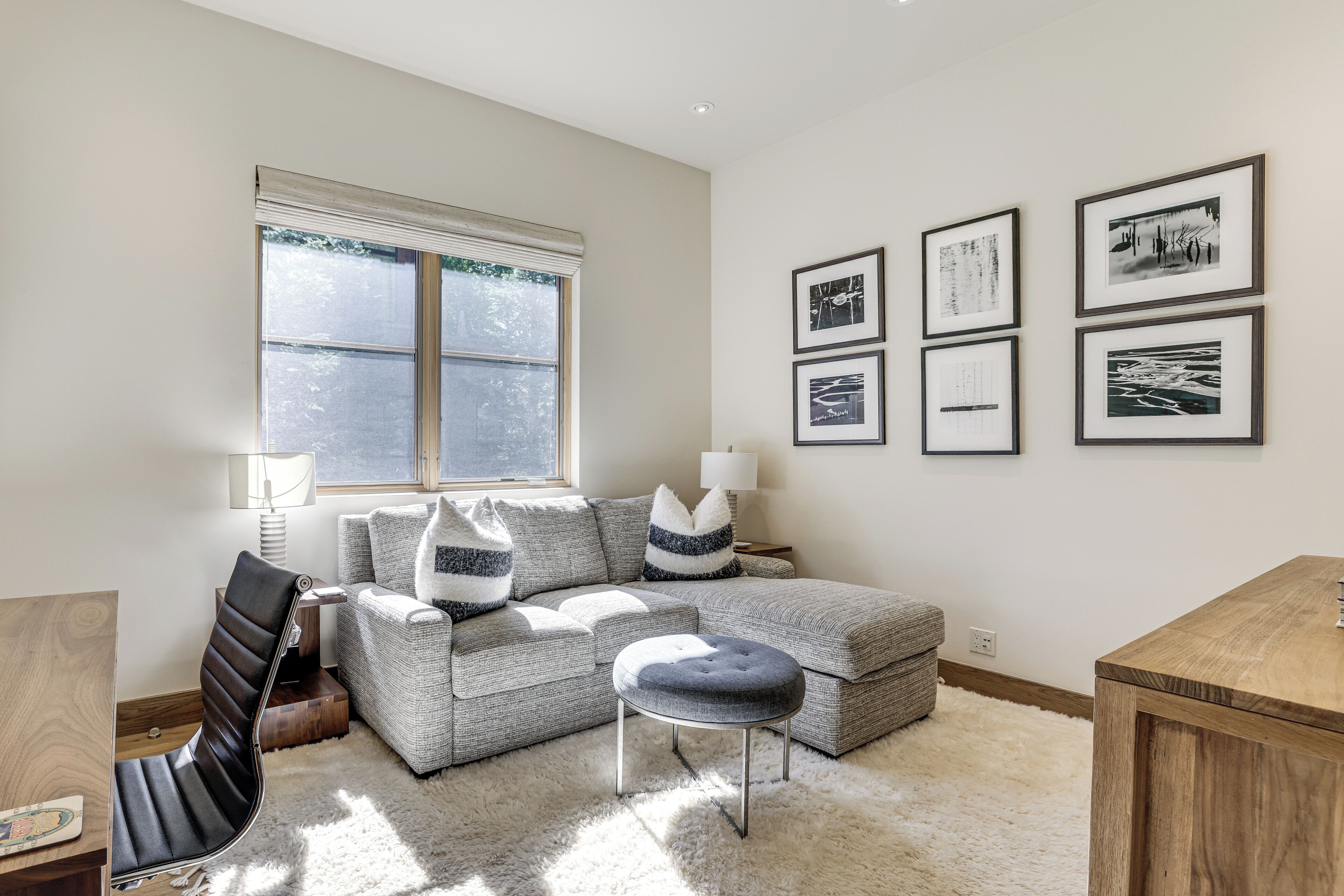 A modern living room with a sofa, ottoman, and a wooden side table.
