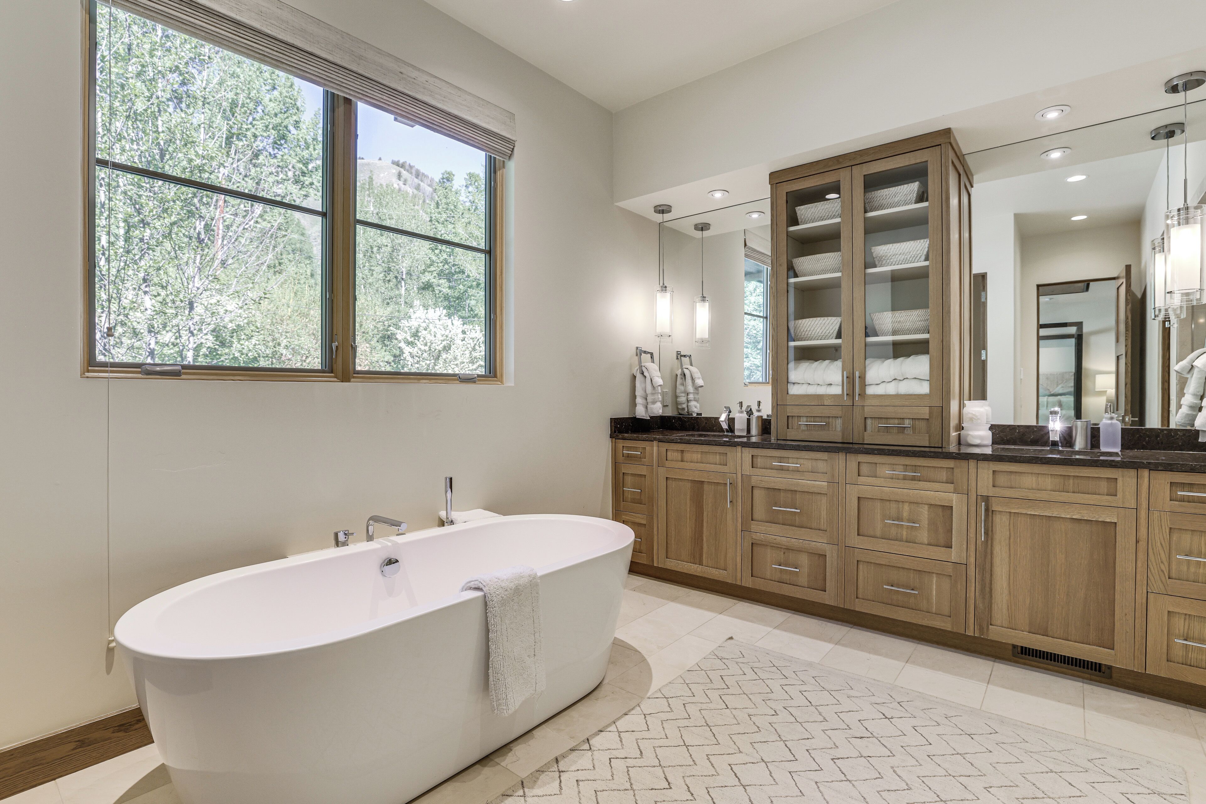 Une salle de bain moderne avec une baignoire sur pieds, des meubles en bois et une grande fenêtre.