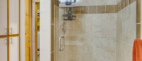 A bathroom with a shower, a towel rack, and a mirror.