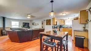 A spacious living area with a sofa, a dining table with stools, and wooden cabinets. - Deck, Trails & Forest Views! Ponderosa Park Cabin (Prescott)