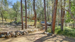 A forested area with a dirt path, rocks, and a vehicle. - Deck, Trails & Forest Views! Ponderosa Park Cabin (Prescott)