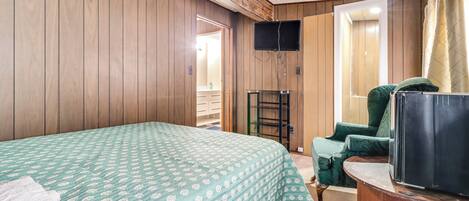Een kamer met een bed, een televisie, een stoel en een houten wand.