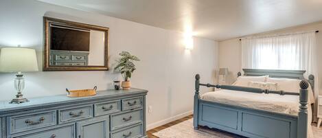 A bedroom with a bed, dresser, mirror, lamp, and potted plant.