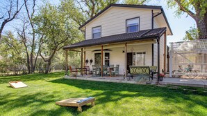 Ein zweistöckiges Haus mit einer Veranda, einer Terrasse und Gartenmöbeln, sowie ein Fahrrad im Hintergrund.