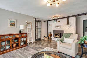 A living room with a fireplace, a sofa, a cabinet with glass doors, and a ladder. - Colorado Countryside Living 7 Mi to Chatfield Res! (Louviers)