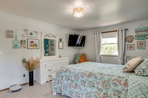 Un dormitorio con cama, cómoda, televisor y adornos en la pared.