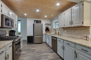 Una cocina con armarios blancos, un refrigerador de acero inoxidable, un horno empotrado y un microondas.