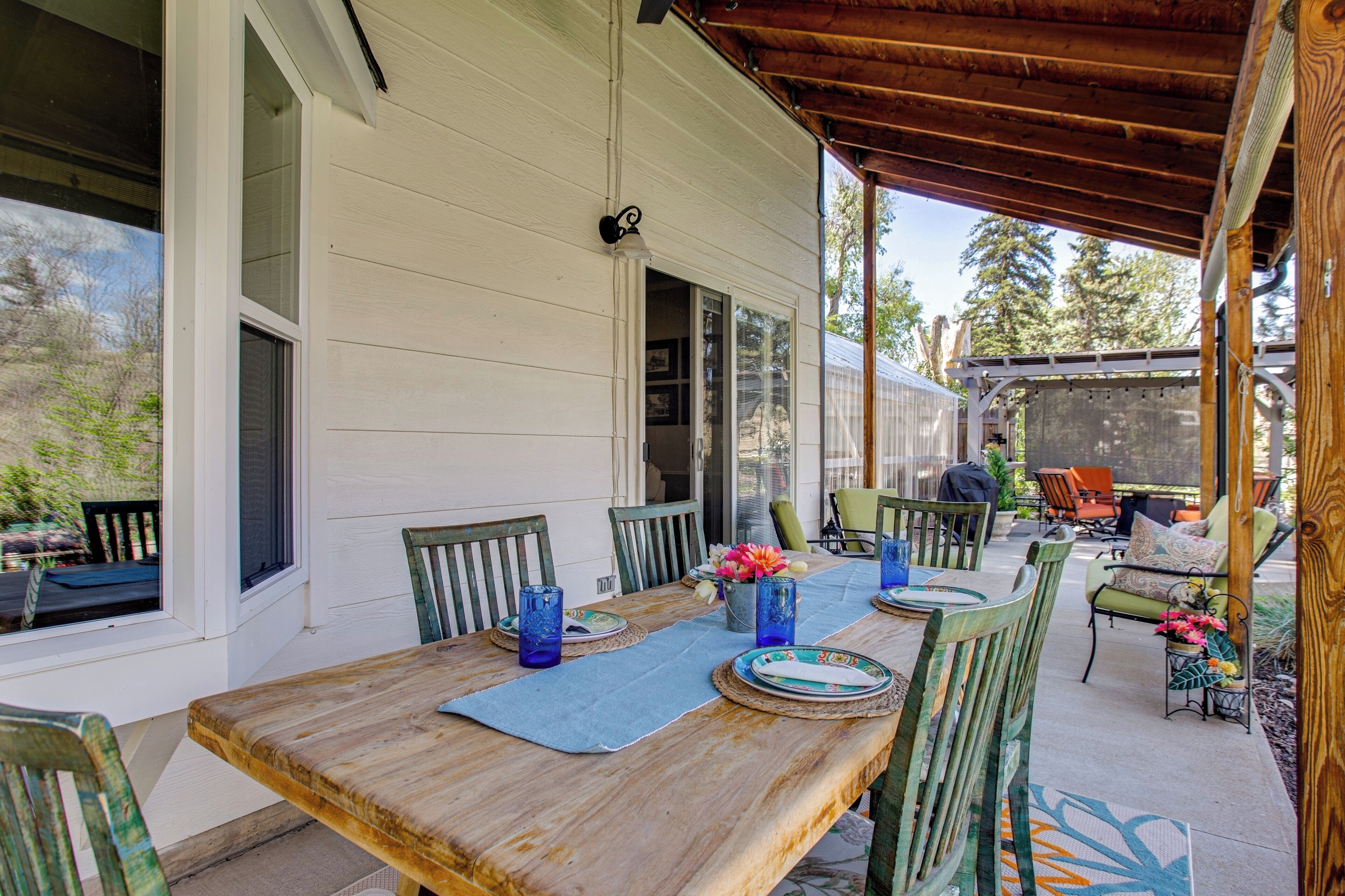A wooden dining table with chairs, a covered patio area, and a view of the outdoors.
