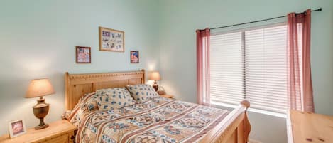 A bedroom with a bed, nightstands, a ceiling fan, a window with blinds, and wall decorations.