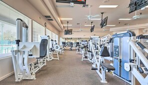 A gym with various exercise machines, large windows, and ceiling fans. - Patio & Grill! Resort-style Sun Lakes Escape (Chandler)