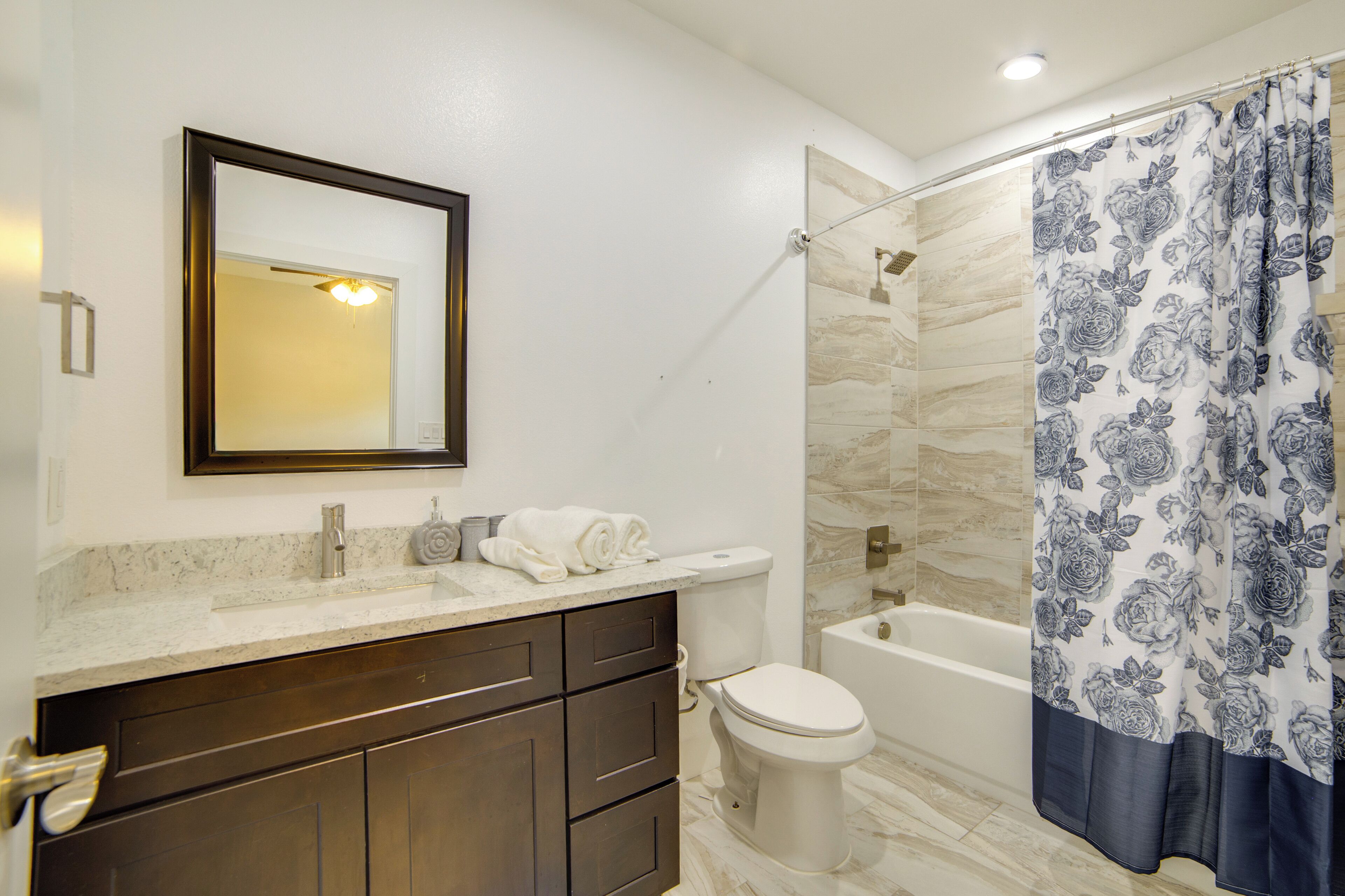A bathroom with a toilet, sink, mirror, and shower curtain.