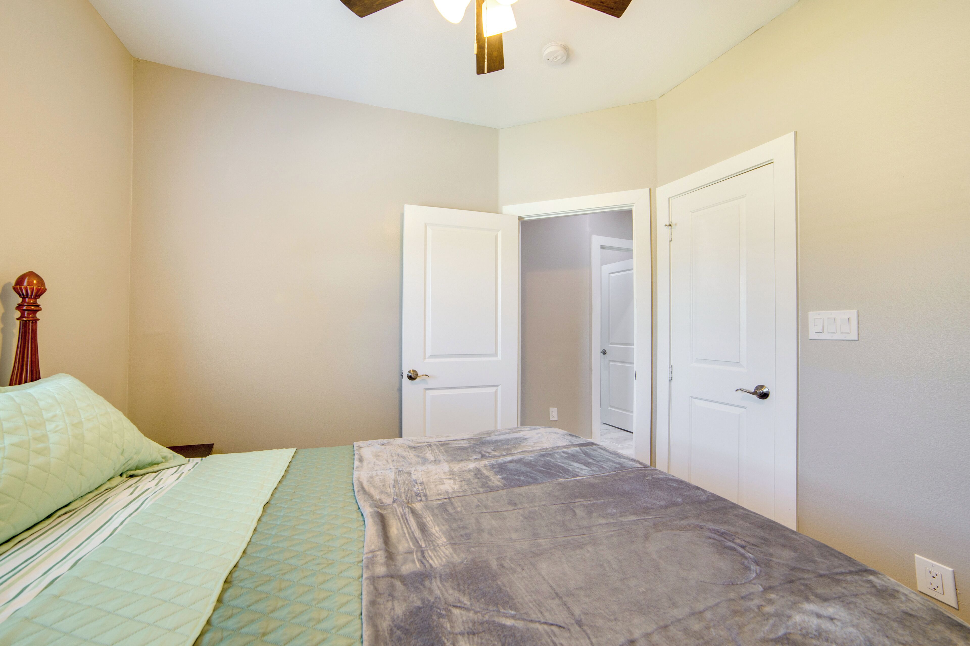 A bedroom with a bed, two doors, and a ceiling fan.