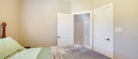 A bedroom with a bed, two doors, and a ceiling fan.