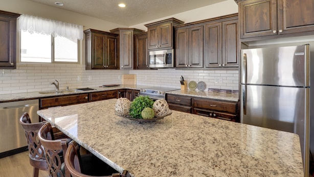 Una cocina con encimeras de granito, electrodomésticos de acero inoxidable y gabinetes de madera.