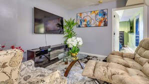 A living room with a flat-screen TV, a glass coffee table, a beige sofa, and a floral-patterned couch. - Walkable Extended Base 2 Mi to Dtwn & Penn Station (Newark)