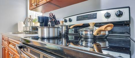 A kitchen with wooden cabinets, a stainless steel stove, and a pot on the counter.