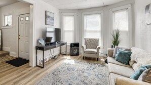 A living room with a sofa, a television, a speaker, and a ceiling fan. - Stroll to Falls & Seneca Casino! Family Getaway (Niagara Falls)