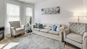 A living room with a beige sofa, a coffee table, and a floor lamp. - Stroll to Falls & Seneca Casino! Family Getaway (Niagara Falls)