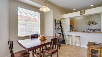 A dining area with a wooden table, chairs, and a window with blinds.