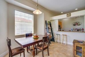 A dining area with a wooden table, chairs, and a window with blinds. - Pool Access & Lake-view Lanai! Port Charlotte Gem (Port Charlotte)
