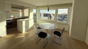 A modern kitchen with a dining area, large windows, and a view of the city. - Sunny Apartment Near the Beach (Koksijde)