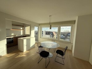 Eine moderne Küche mit Essbereich, großen Fenstern und Blick auf die Stadt.