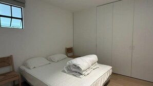 A bedroom with a bed, a chair, a wardrobe, and a window. - Sunny Apartment Near the Beach (Koksijde)