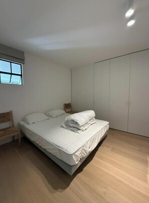 Ein Schlafzimmer mit Bett, Stuhl, Schrank und Fenster.