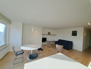 Ein moderner Wohnbereich mit Essplatz, einer Couch und einem Fernseher.