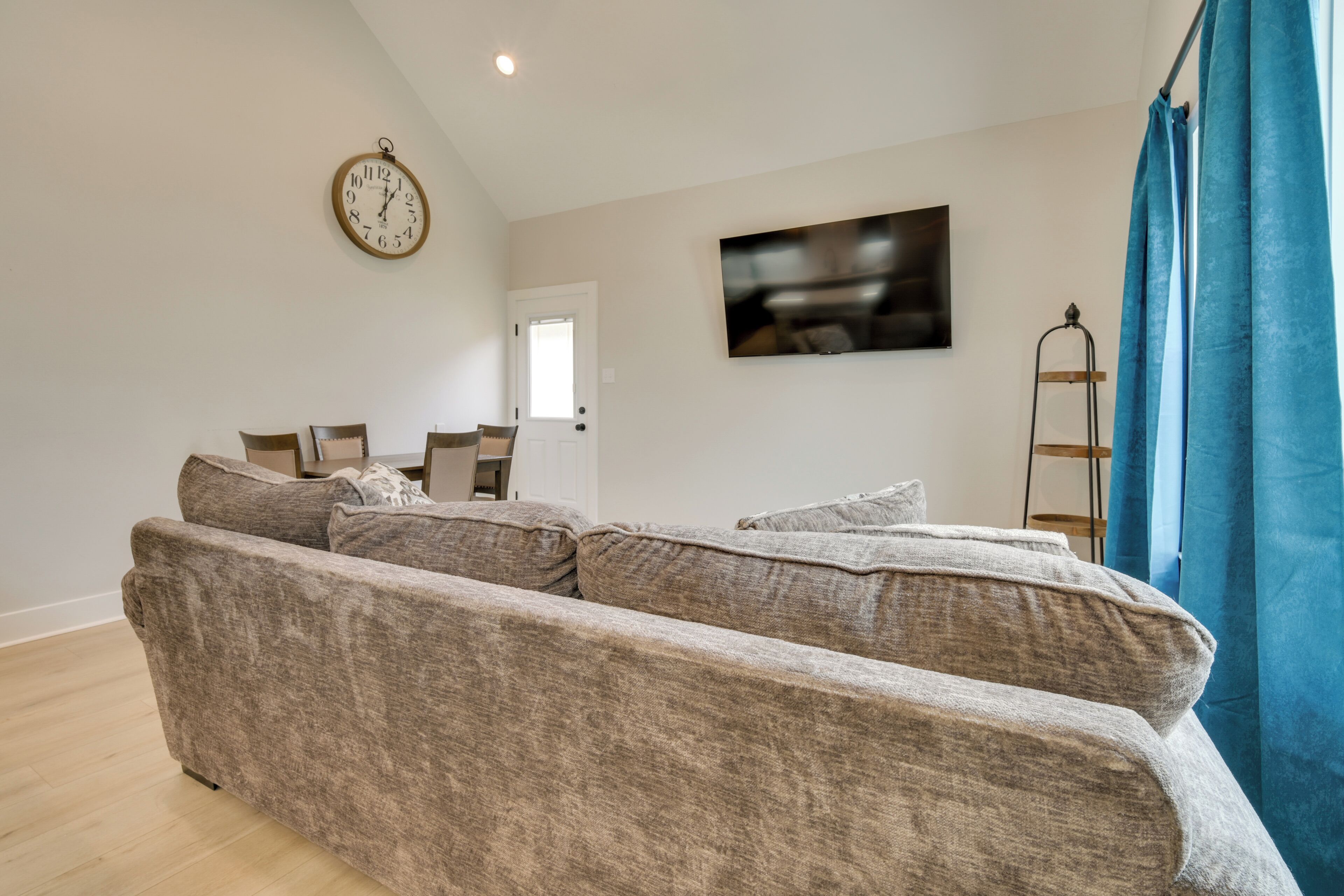 A living room with a sofa, a clock, a television, and a door.