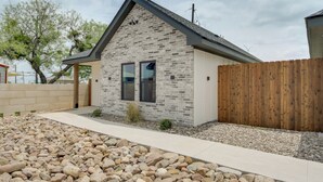 A modern house with a stone facade, a wooden fence, and a gravel driveway. - Near AFB & Medical Center: Modern San Angelo Home (San Angelo)