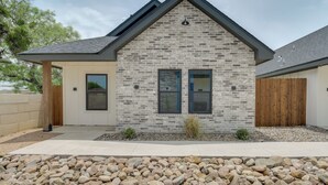 A modern house with a stone facade, two windows, a wooden door, and a fenced yard. - Near AFB & Medical Center: Modern San Angelo Home (San Angelo)