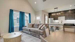 A modern living room with a sofa, a coffee table, and a kitchen area with bar stools. - Near AFB & Medical Center: Modern San Angelo Home (San Angelo)