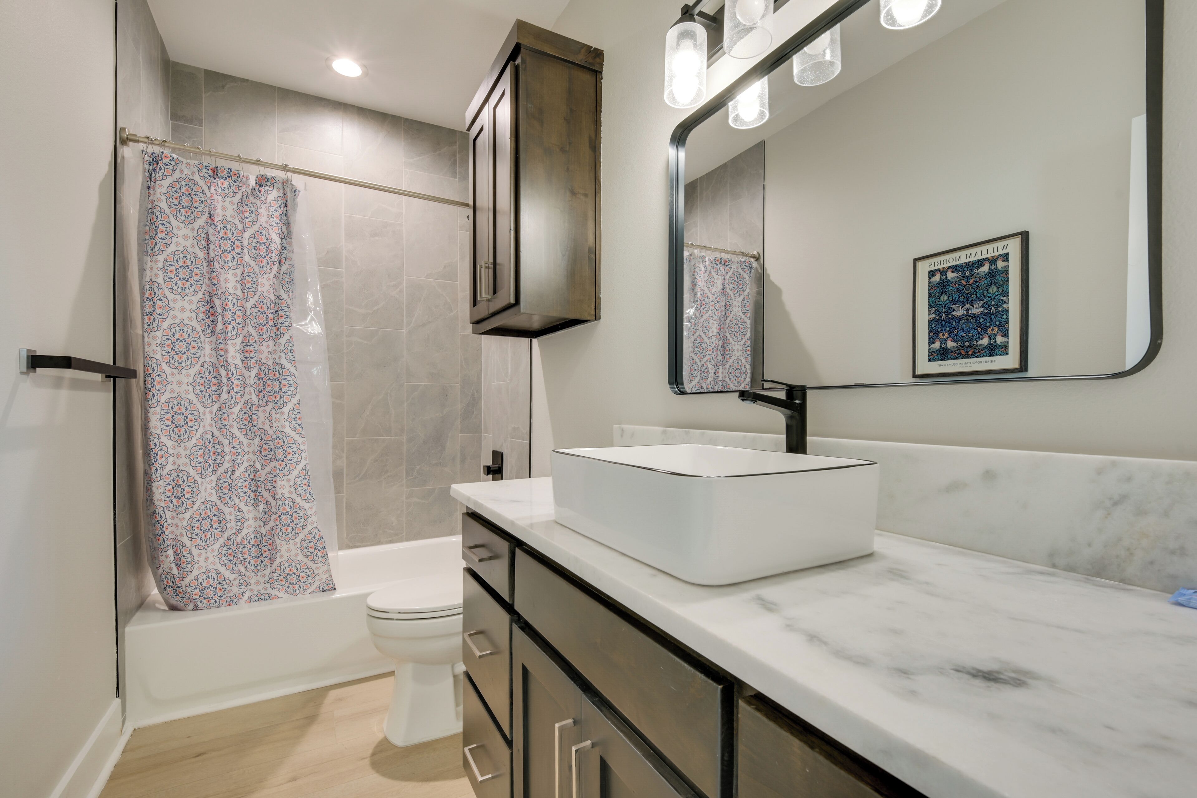 Une salle de bain moderne avec une baignoire, des toilettes et un grand miroir au-dessus du lavabo.