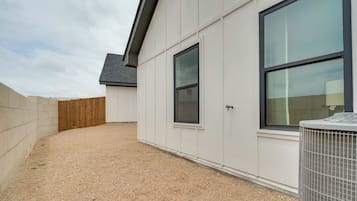 Un edificio con vialetto in ghiaia, recinzione in legno e condizionatore d'aria.