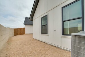 A building with a gravel driveway, a wooden fence, and an air conditioning unit. - 7 Mi to Goodfellow Afb: Home w/ Fenced Yard (San Angelo)