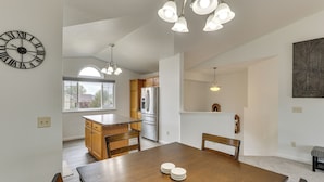 A modern kitchen with wooden cabinets, a stainless steel refrigerator, and a dining area with a wooden table and chairs. - 4 Mi to Ellsworth Afb! Suburban Home for Families (Box Elder)