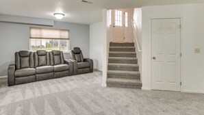 A carpeted room with a sofa, a window with blinds, a staircase, and a door. - 4 Mi to Ellsworth Afb! Suburban Home for Families (Box Elder)